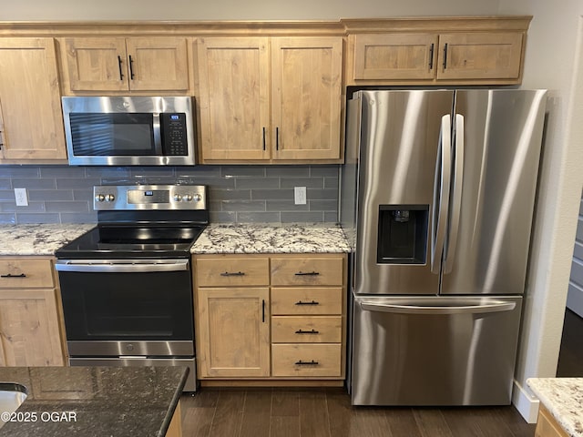 kitchen with appliances with stainless steel finishes, dark wood-type flooring, light stone counters, and decorative backsplash