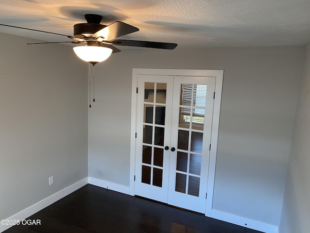 empty room featuring french doors, ceiling fan, and dark wood-type flooring