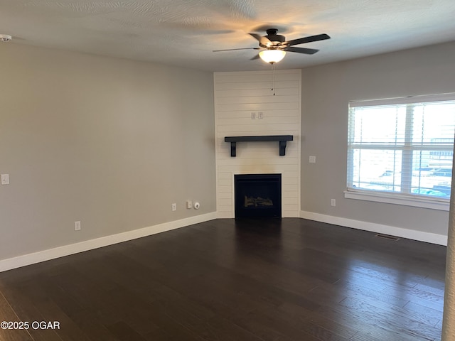 unfurnished living room featuring a textured ceiling, a fireplace, dark hardwood / wood-style floors, and ceiling fan