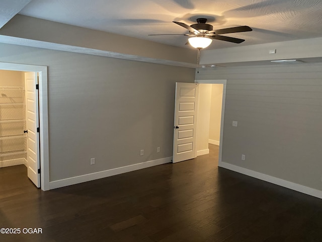 unfurnished bedroom featuring dark hardwood / wood-style floors, a spacious closet, ceiling fan, and a closet