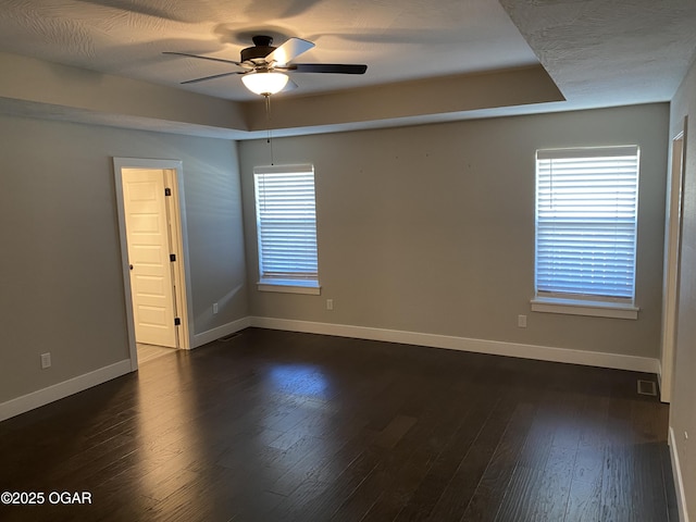 spare room featuring dark hardwood / wood-style floors, a healthy amount of sunlight, and a tray ceiling