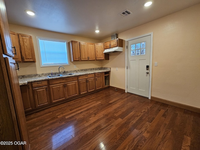 kitchen featuring light stone countertops, sink, and dark wood-type flooring