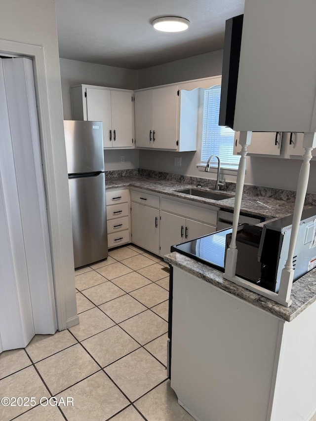 kitchen featuring light tile patterned flooring, stainless steel fridge, sink, and white cabinets