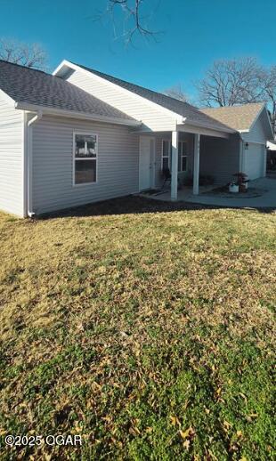 back of house with a garage and a lawn