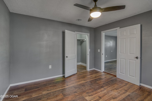 unfurnished bedroom featuring ceiling fan, dark hardwood / wood-style flooring, a closet, and a textured ceiling