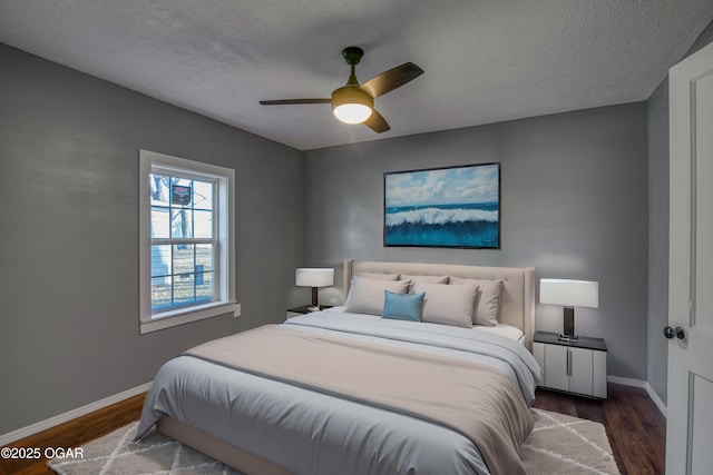 bedroom with dark hardwood / wood-style floors, a textured ceiling, and ceiling fan