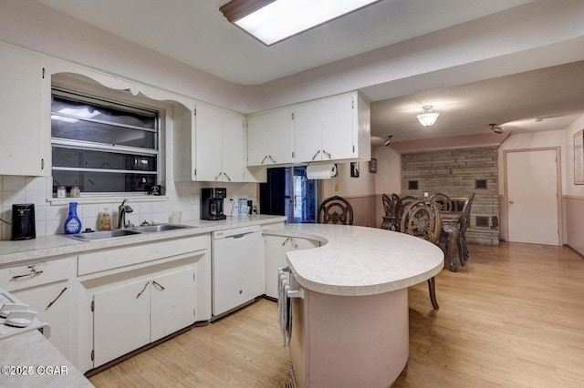 kitchen with tasteful backsplash, white cabinetry, dishwasher, sink, and light wood-type flooring