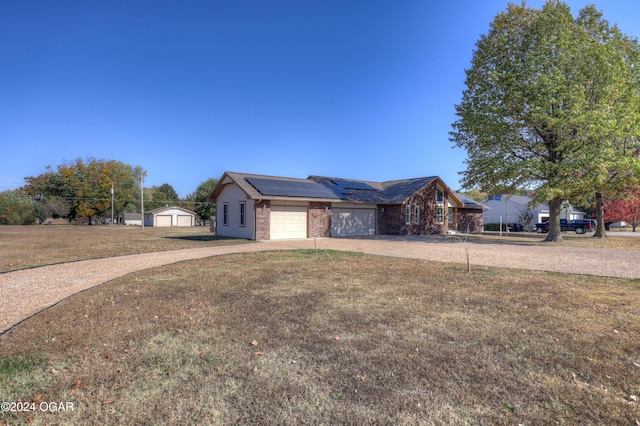 single story home with a garage, a front yard, and solar panels