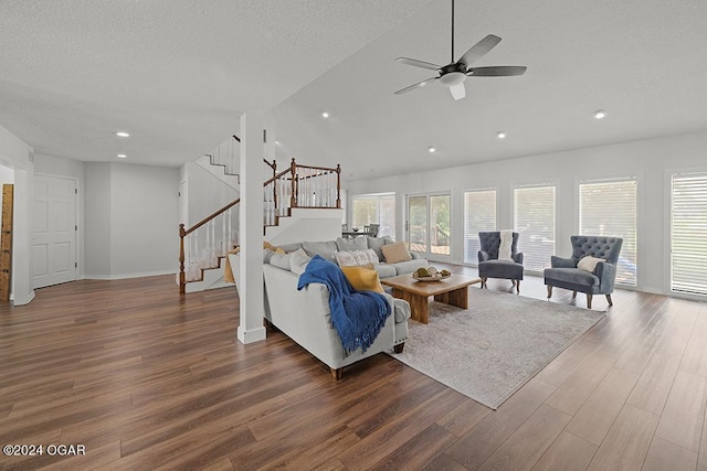 living room featuring ceiling fan, dark wood-type flooring, and a textured ceiling