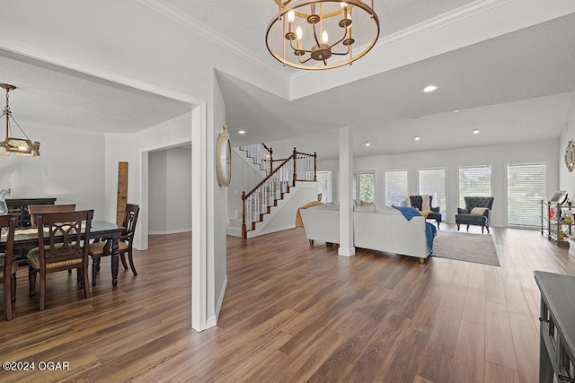 living room featuring a notable chandelier, crown molding, dark wood-type flooring, and a textured ceiling