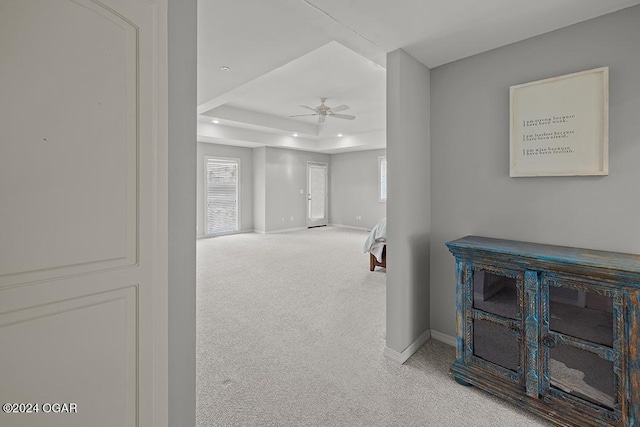 hall with carpet floors and a tray ceiling