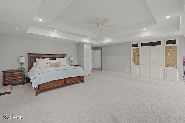 bedroom with ceiling fan, a raised ceiling, and light colored carpet