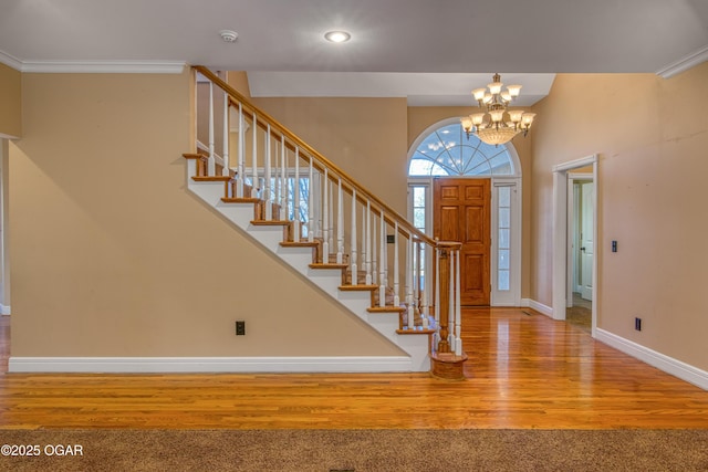 foyer with an inviting chandelier, ornamental molding, and hardwood / wood-style floors