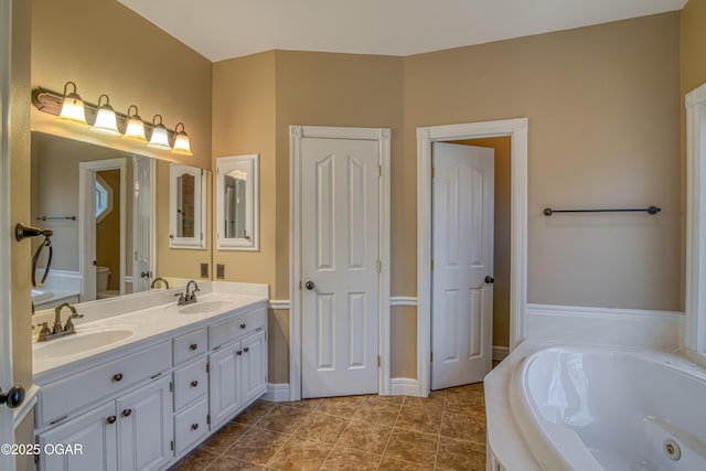 bathroom with tile patterned flooring, vanity, tiled bath, and toilet