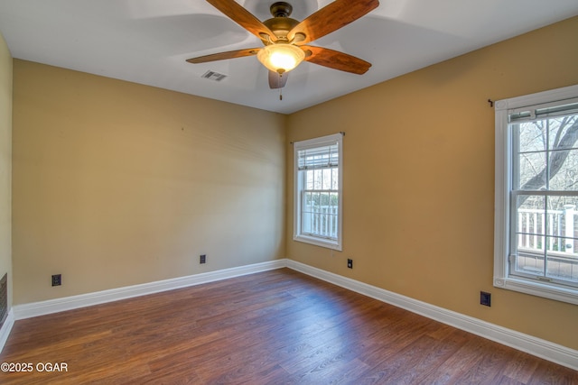 empty room featuring a wealth of natural light, dark hardwood / wood-style floors, and ceiling fan