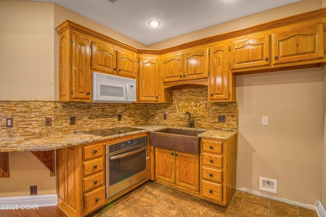 kitchen with sink, backsplash, light stone counters, black electric cooktop, and oven