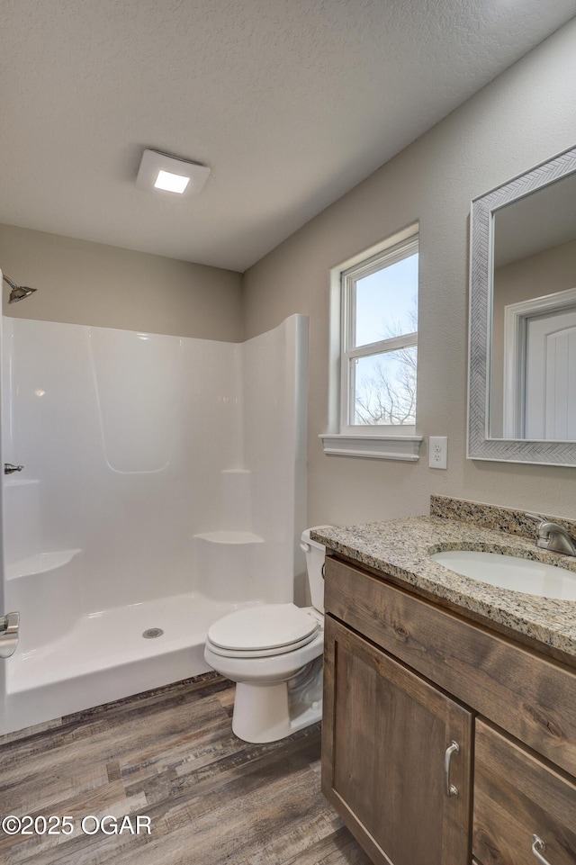 bathroom featuring hardwood / wood-style flooring, vanity, walk in shower, toilet, and a textured ceiling