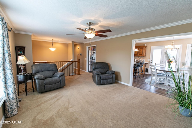 carpeted living room featuring crown molding, ceiling fan with notable chandelier, and a textured ceiling