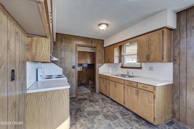 kitchen with sink, wooden walls, white electric stove, and a textured ceiling