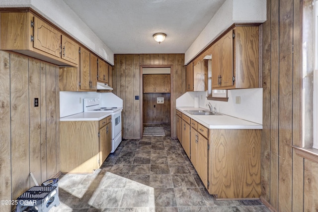 kitchen featuring wooden walls, sink, a textured ceiling, and electric range