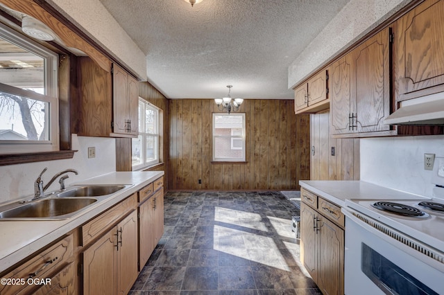 kitchen featuring sink, pendant lighting, electric range, and wooden walls