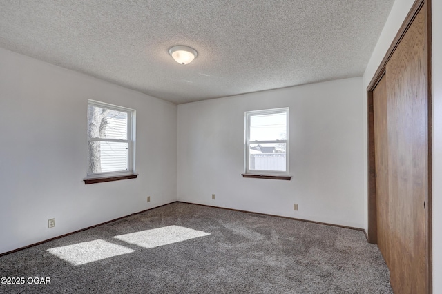 carpeted spare room featuring a wealth of natural light and a textured ceiling