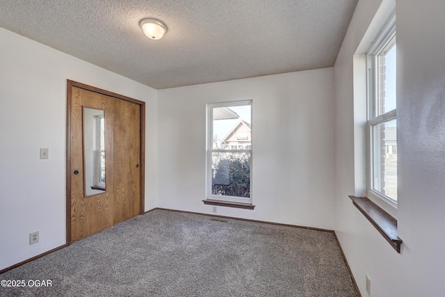 unfurnished room featuring a textured ceiling and carpet flooring