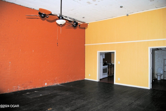 interior space featuring dark hardwood / wood-style flooring, ceiling fan, and brick wall