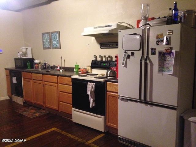 kitchen with white refrigerator, dark hardwood / wood-style flooring, sink, and range with electric stovetop