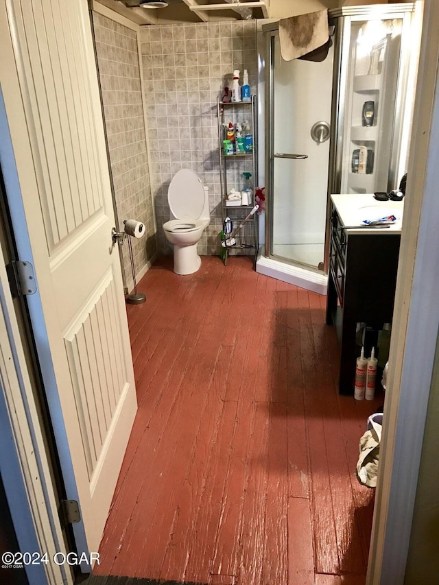 bathroom with vanity, hardwood / wood-style flooring, a shower with door, and toilet