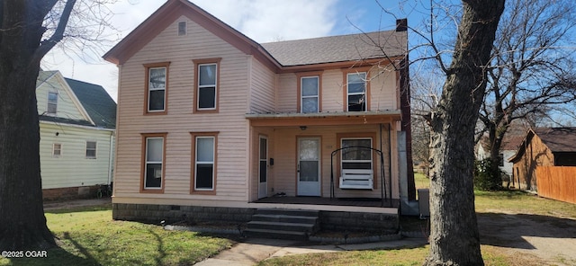 view of front facade featuring covered porch, a chimney, roof with shingles, and fence