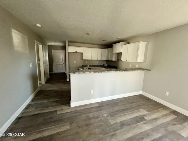 kitchen with hardwood / wood-style flooring, light stone counters, a textured ceiling, white cabinets, and kitchen peninsula