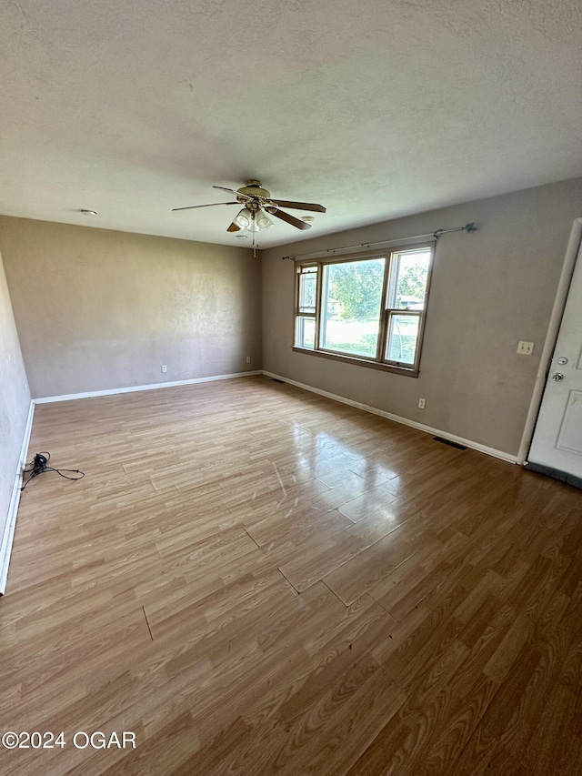 spare room featuring ceiling fan, light hardwood / wood-style flooring, and a textured ceiling