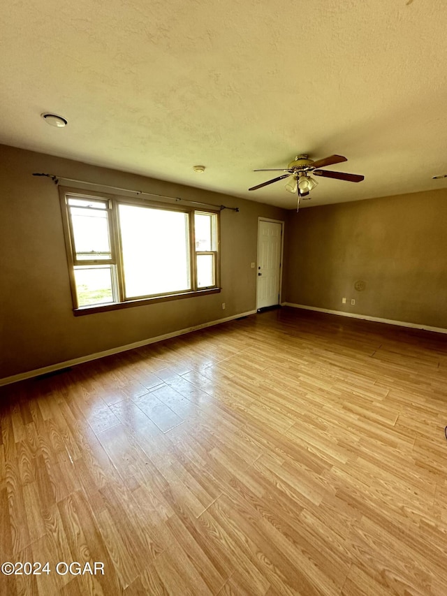 spare room featuring ceiling fan, light hardwood / wood-style flooring, and a textured ceiling