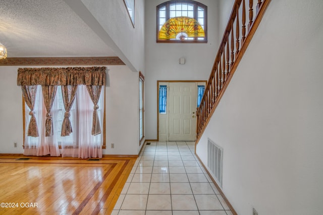 tiled entrance foyer featuring a towering ceiling and a textured ceiling