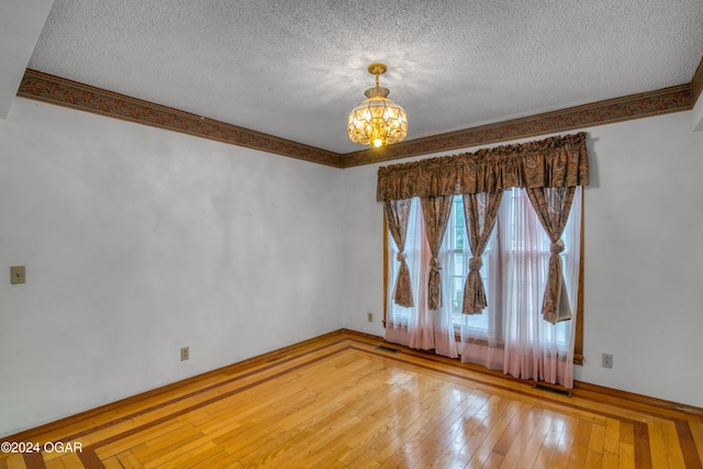 empty room featuring hardwood / wood-style floors, a textured ceiling, and a chandelier