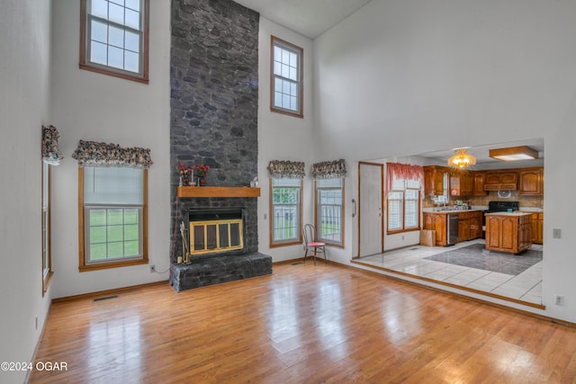 unfurnished living room featuring a towering ceiling, a fireplace, and light hardwood / wood-style floors