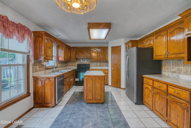 kitchen with sink, an inviting chandelier, light tile patterned floors, appliances with stainless steel finishes, and a kitchen island