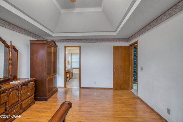 bedroom with a raised ceiling and light wood-type flooring