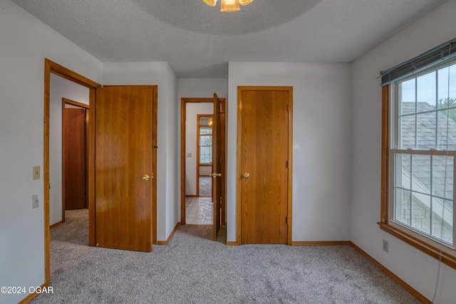 unfurnished bedroom with light carpet and a textured ceiling