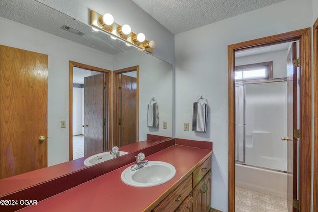 bathroom with vanity, shower / bath combination with glass door, and a textured ceiling