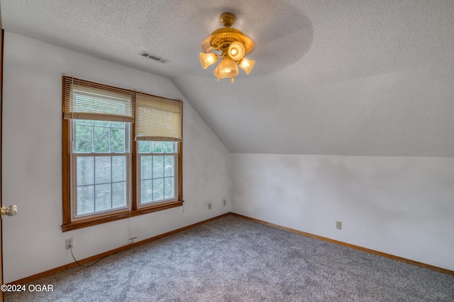 additional living space with ceiling fan, lofted ceiling, carpet, and a textured ceiling