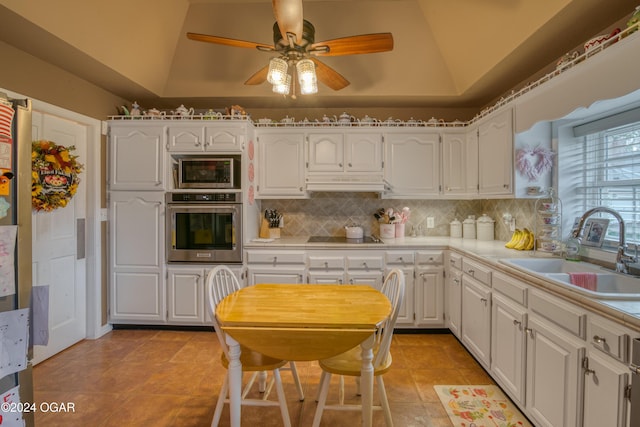 kitchen with lofted ceiling, appliances with stainless steel finishes, sink, and white cabinets