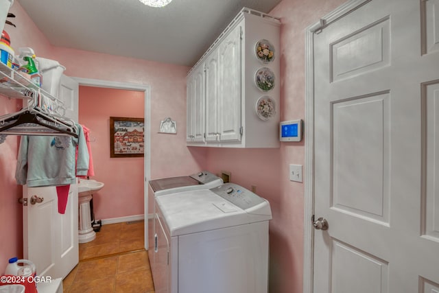 laundry area with cabinets, washing machine and dryer, and light tile patterned floors