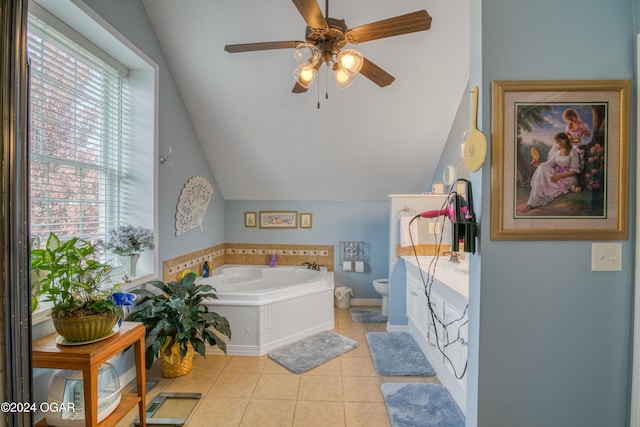 bathroom featuring tile patterned flooring, vanity, a tub to relax in, vaulted ceiling, and toilet