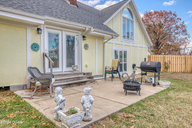 rear view of property featuring a yard, a patio, and an outdoor fire pit