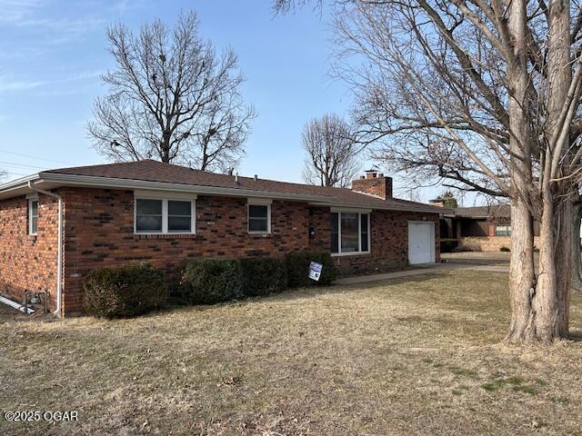 rear view of property featuring a garage and a yard