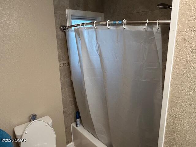 bathroom with shower / bath combo and toilet