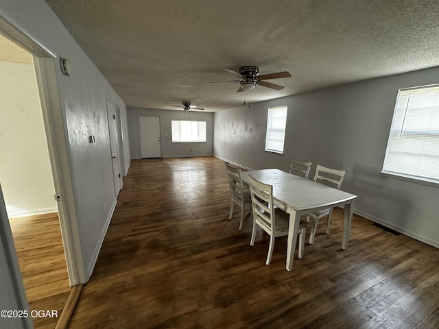 unfurnished dining area featuring ceiling fan, dark hardwood / wood-style floors, and a textured ceiling