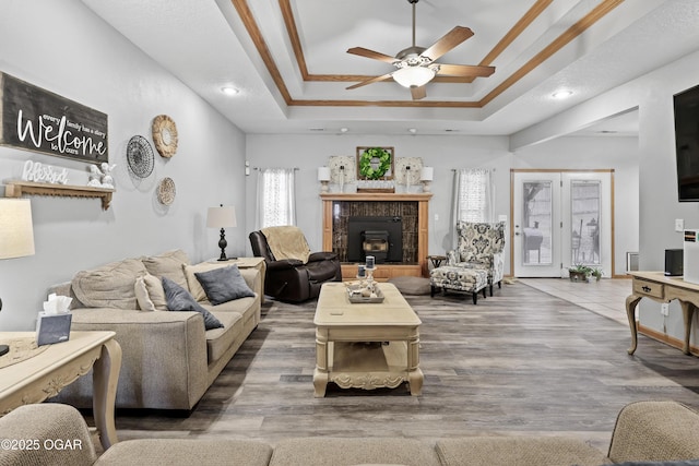 living room with crown molding, hardwood / wood-style floors, a tray ceiling, and ceiling fan